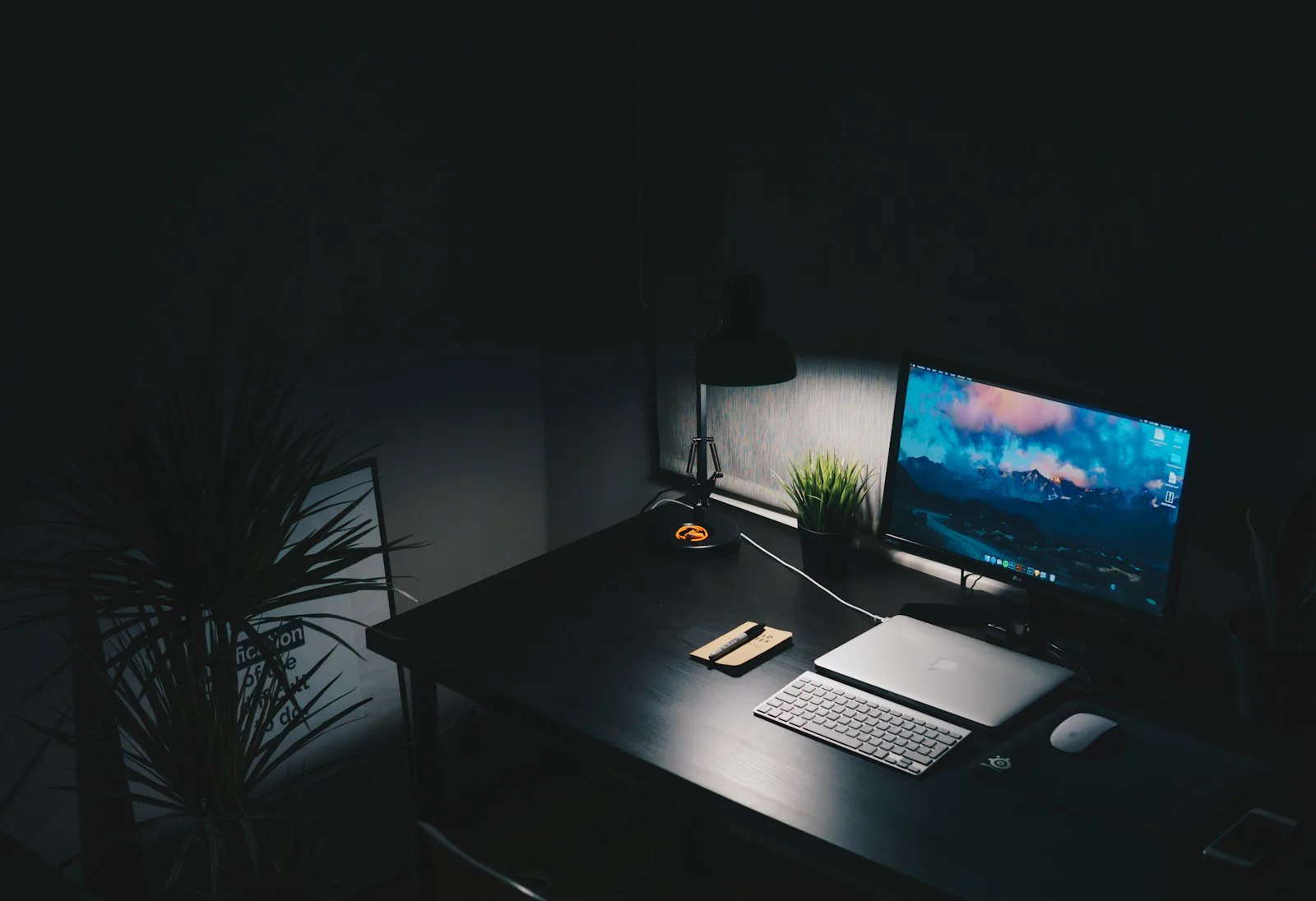 Mesa escura com monitor e laptop